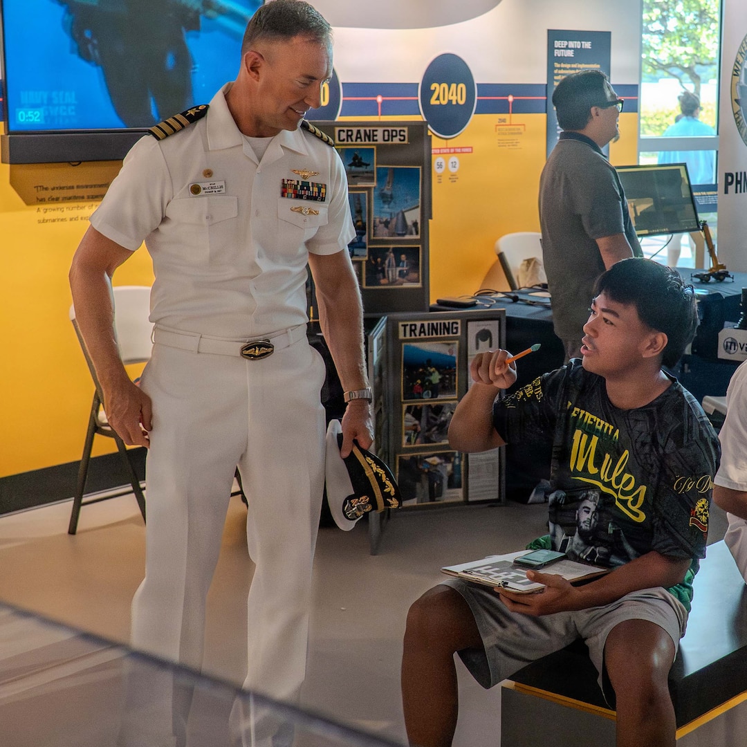 Capt. Ryan McCrillis, commander of Pearl Harbor Naval Shipyard and Intermediate Maintenance Facility, chats with a student about various trades during a mini-trades fair at the Pacific Fleet Submarine Museum on July 15, 2026.