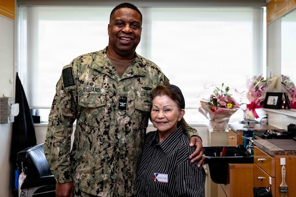 Capt. Richard Gilliard Jr., left, commanding officer, U.S. Naval Hospital Okinawa, and Haru Uchira, USNHO’s barber, pose for a photo together in USNHO’s barber shop at Camp Foster, Okinawa, Japan, Aug. 13, 2026. Uchira retired after 56 years of service, witnessing USNHO’s transition from U.S. Army to U.S. Navy-operated in 1977, multiple organizational redesignations, and its relocation from Camp Lester to Camp Foster in 2013. (U.S. Navy photo by Mass Communication Specialist 1st Class Simon Pike)