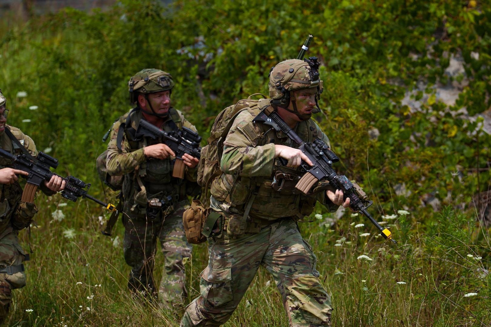 An Indiana National Guardsman assigned to the 1st Battalion, 151st Infantry Regiment, and Slovak Armed Forces soldiers run toward an objective during an assault at a Combat Readiness Exercise at Muscatatuck Training Center near Butlerville, Ind., July 26.