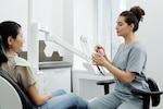 Dentist shows a patient a dental model while the patient sits in the dentist's chair