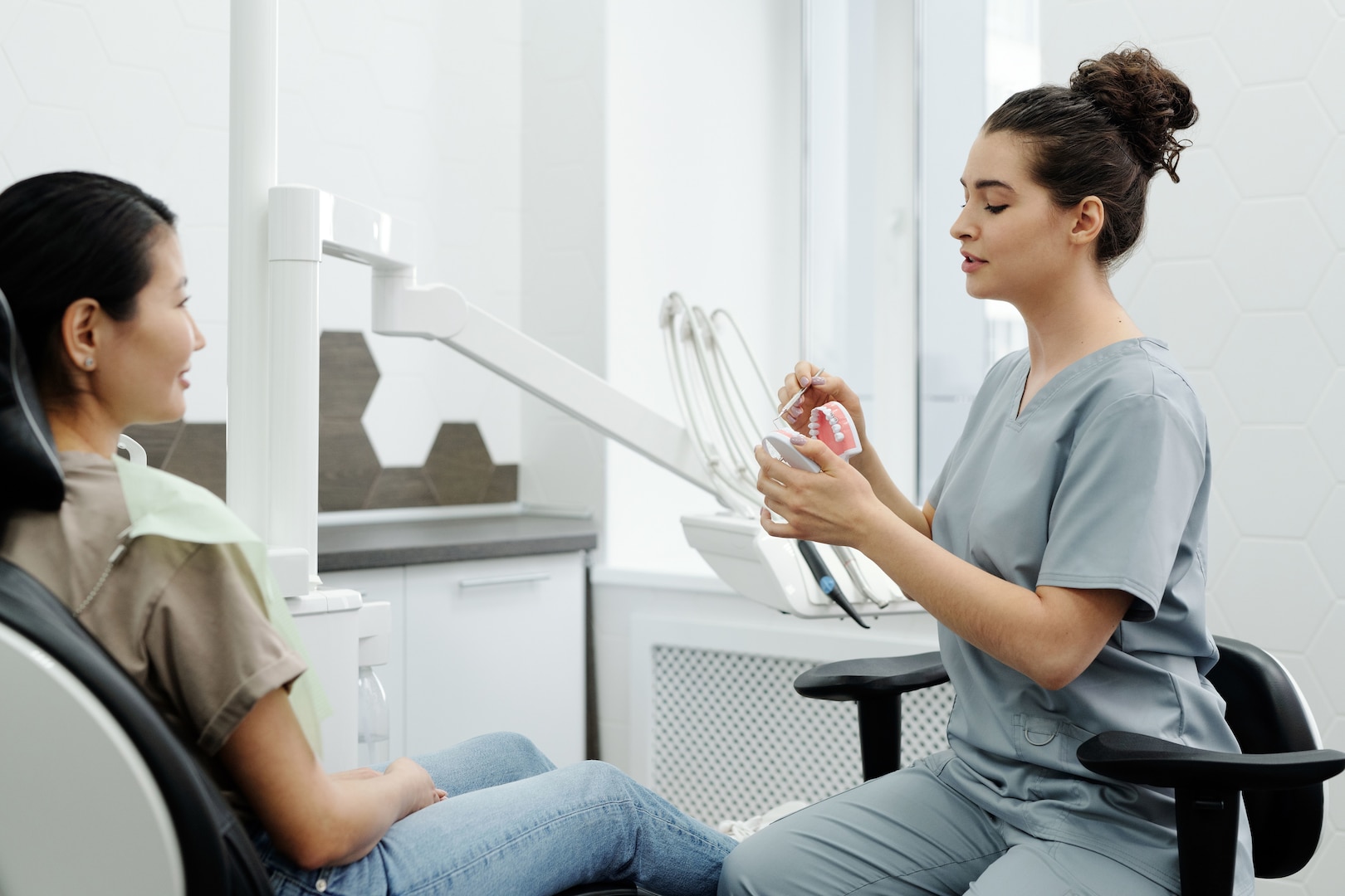 Dentist shows a patient a dental model while the patient sits in the dentist's chair