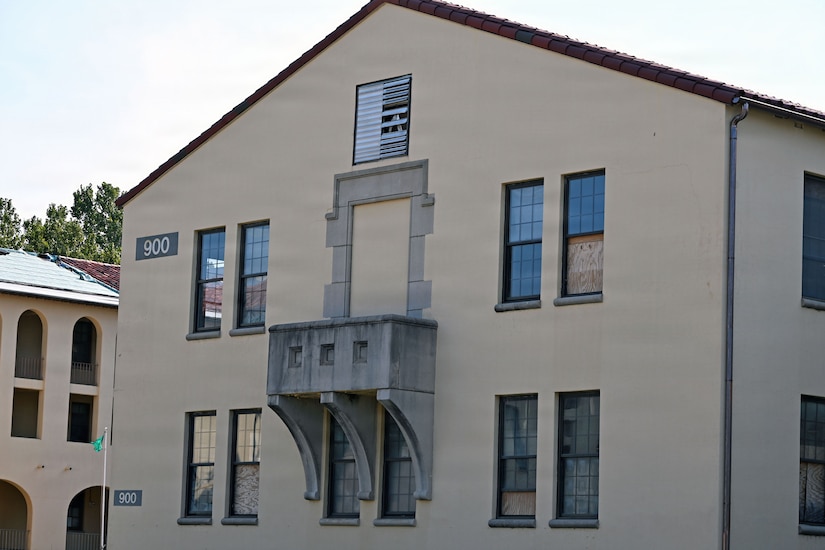 A beige building with the number 900 on it. Another building is just behind it.