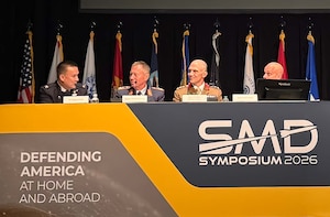 Military and civilian leaders speak at a conference.