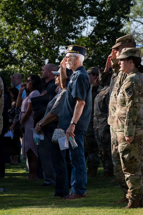 a group people are standing either saluting or with their right hand on their heart