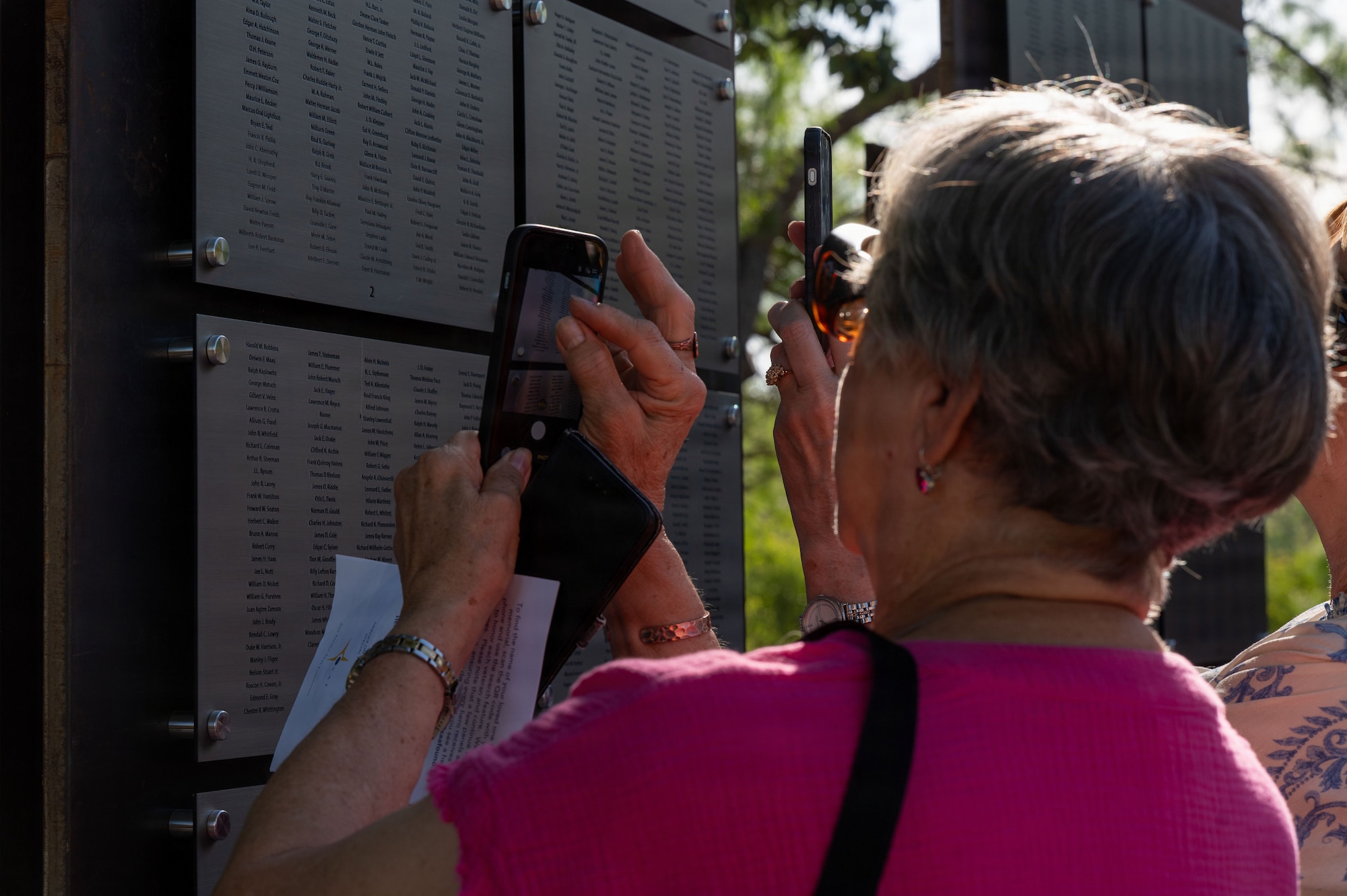 A woman uses her phone to take a photo of a memorial stone