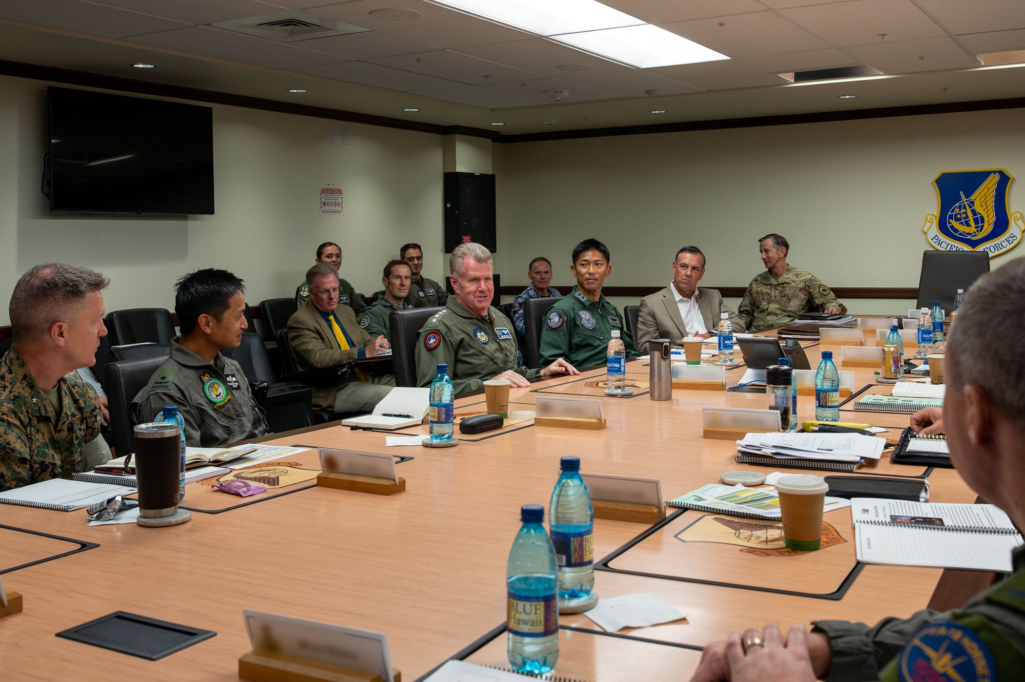 Military officers speak around a table