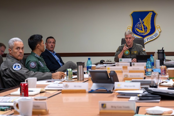 Military officers speak around a table