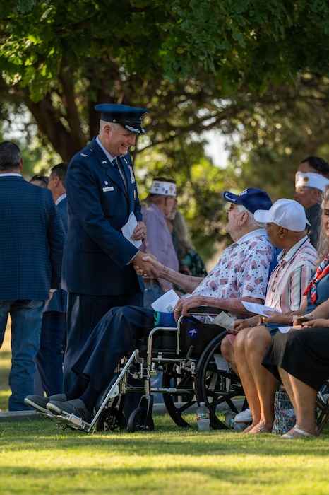 A service member shakes the hand of a man in a wheelchair
