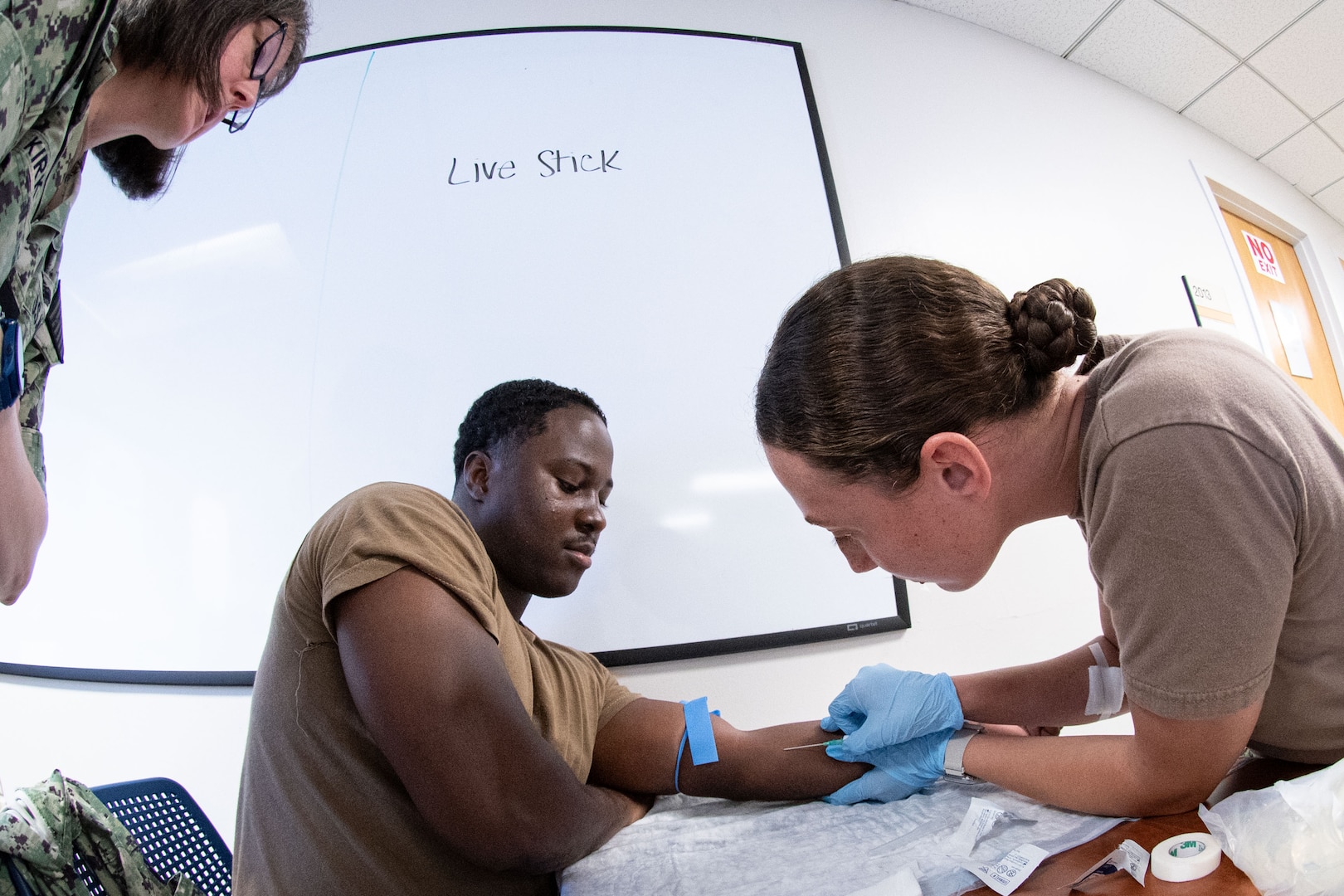 *Training* Navy Capt. Heather Kirk, NMRTC Cherry Point’s Director of Medical Services, left, observes as Hospital Corpsman 3rd Class Lauren Krietemeyer, right, inserts an IV needle into a fellow corpsman’s arm during “Live Stick” training conducted Thursday, August 20, 2026, at Navy Medicine Readiness and Training Command Cherry Point. The Skills Fair evaluated the knowledge of corpsmen assigned to the facility and trained them on competencies and tasks expected of them in an operational environment.