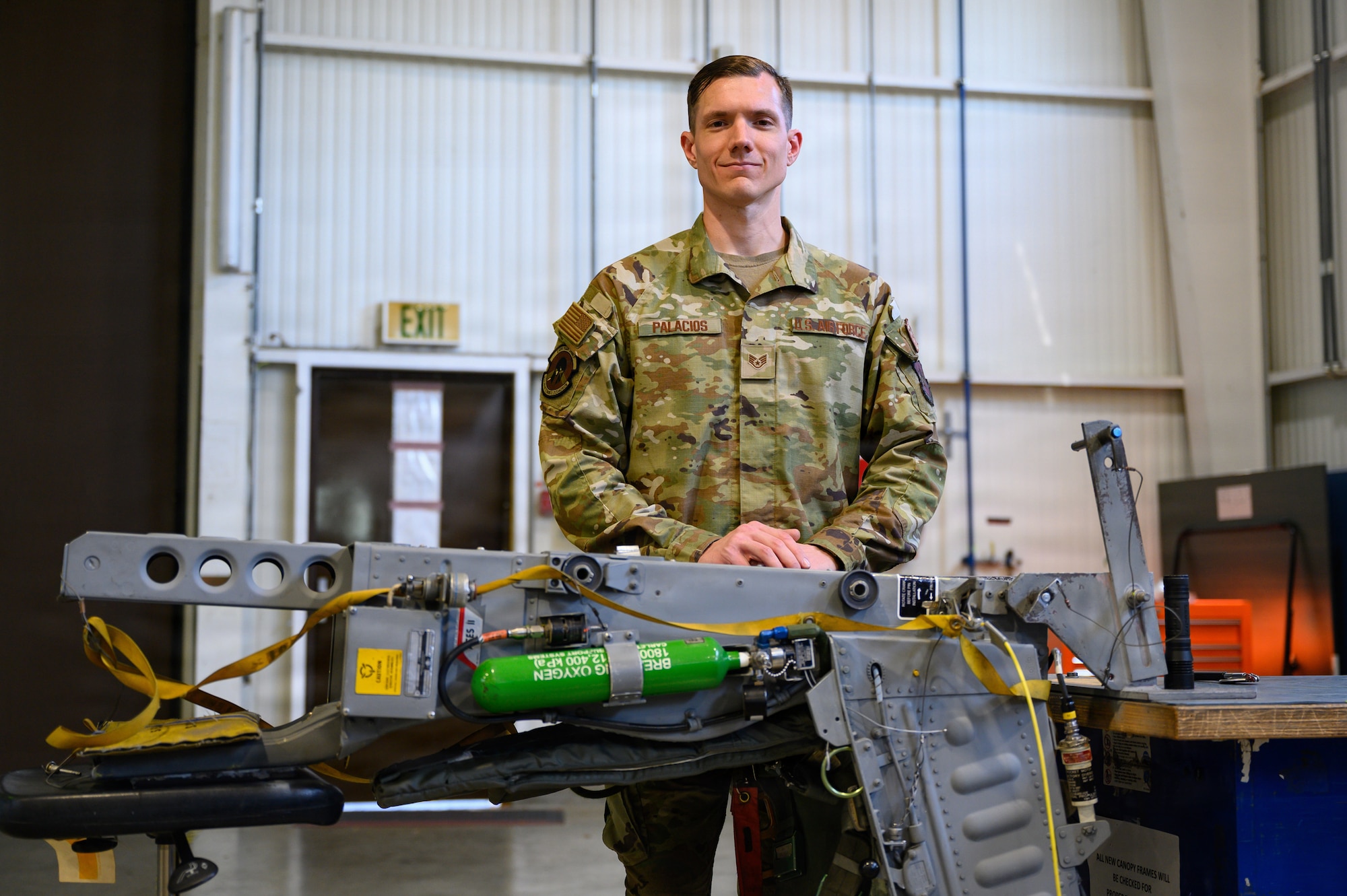 A person poses next to an ejection seat.