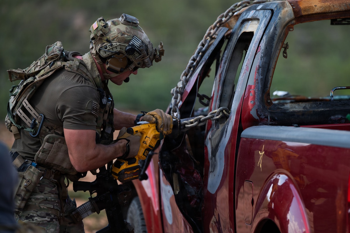 A pararescueman assigned to the 38th Rescue Squadron uses a saw to cut through chains on a vehicle to free a simulated injured person during Operation Iron Covenant near Benson, Ariz., July 22, 2026. The training assessed individual proficiency and team effectiveness under realistic conditions. (U.S. Air Force photo by Airman Najzee Kuzu)