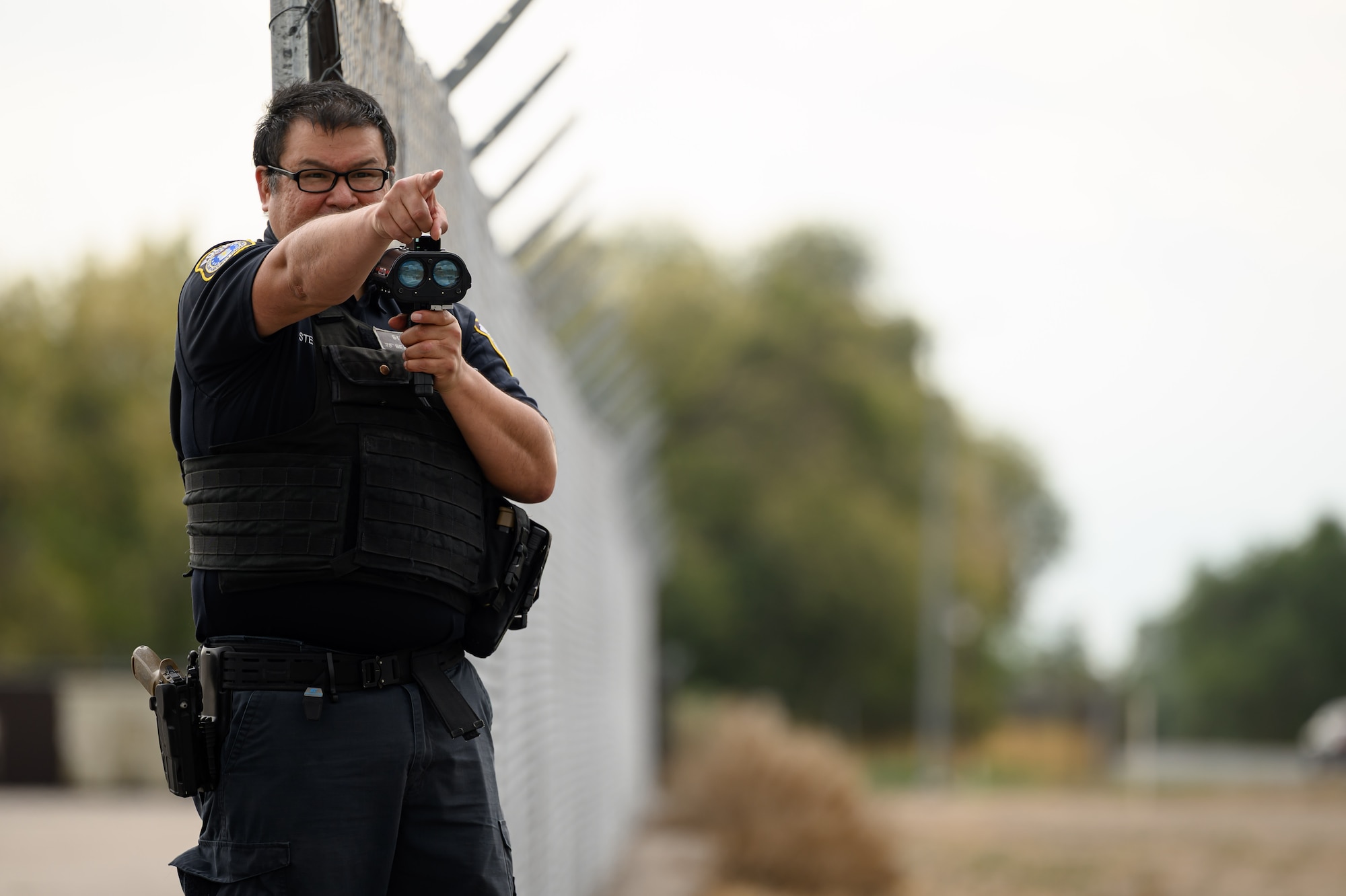 A 75th Security Forces Squadron defender monitors vehicle speeds with a radar device while pointing.