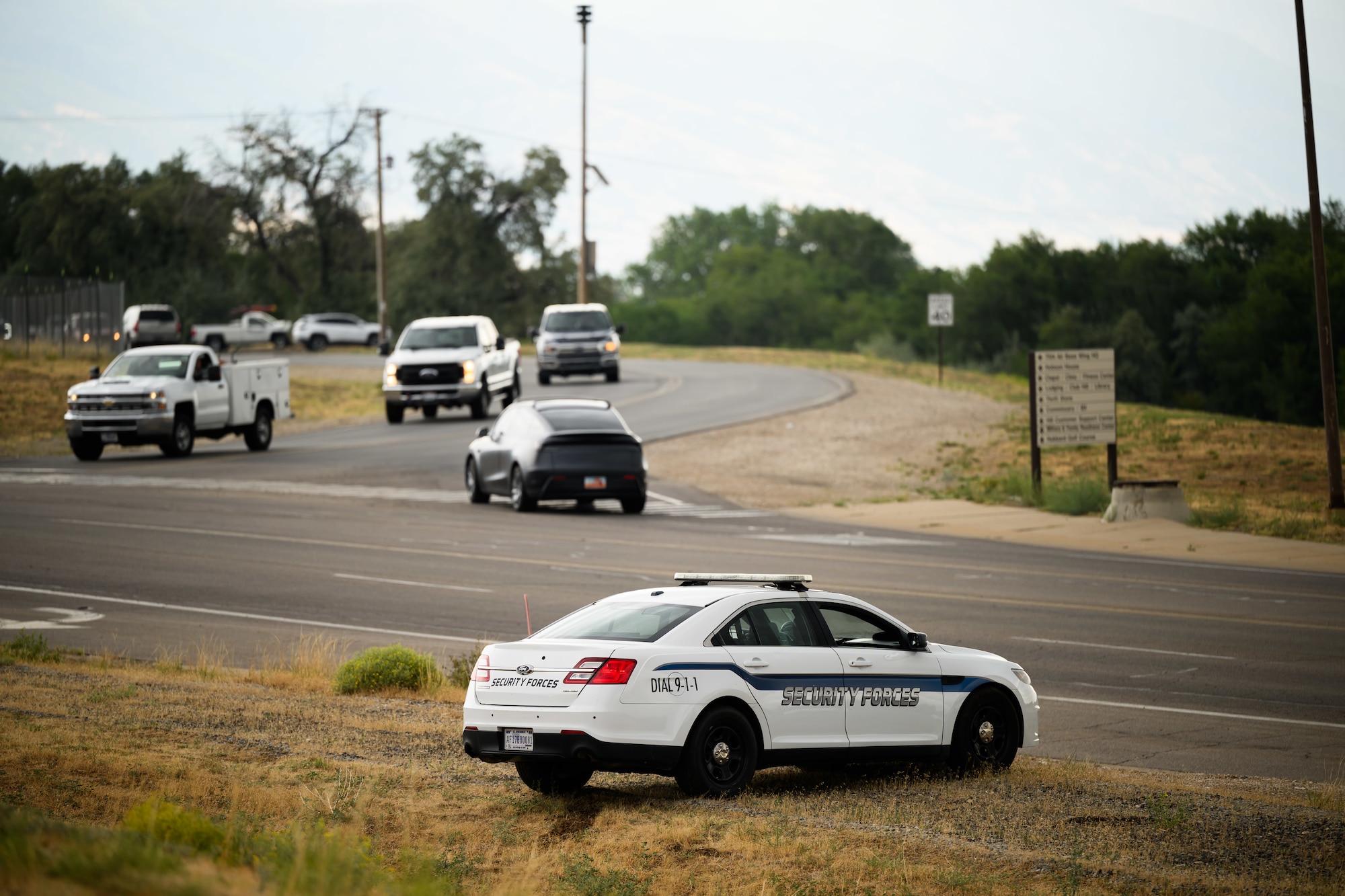 a 75th Security Forces Squadron patrol vehicle is positioned along a roadway during a speed enforcement operation. Other vehicles can be seen on the road in the background.