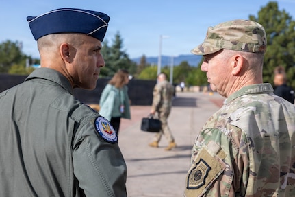 Gen. Gregory Guillot, commander of North American Aerospace Defense Command (NORAD) and U.S. Northern Command (USNORTHCOM), speaks with Gen. Adrian Spain, commander of Air Combat Command, outside of the NORAD and USNORTHCOM headquarters on Peterson Space Force Base, Colorado, Aug. 18, 2026. The commanders met to begin the annual Warfighter Talks, an executive-level engagement focused on synchronizing force presentation, modernizing command and control systems, and enhancing combined readiness to defend North America. (Dept. of War photo by U.S. Air Force Staff Sgt. Colten Tessness)