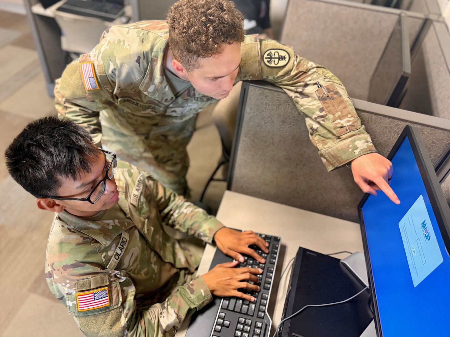 A mental health provider shows a Soldier how to sign in to a mental health portal on a computer.
