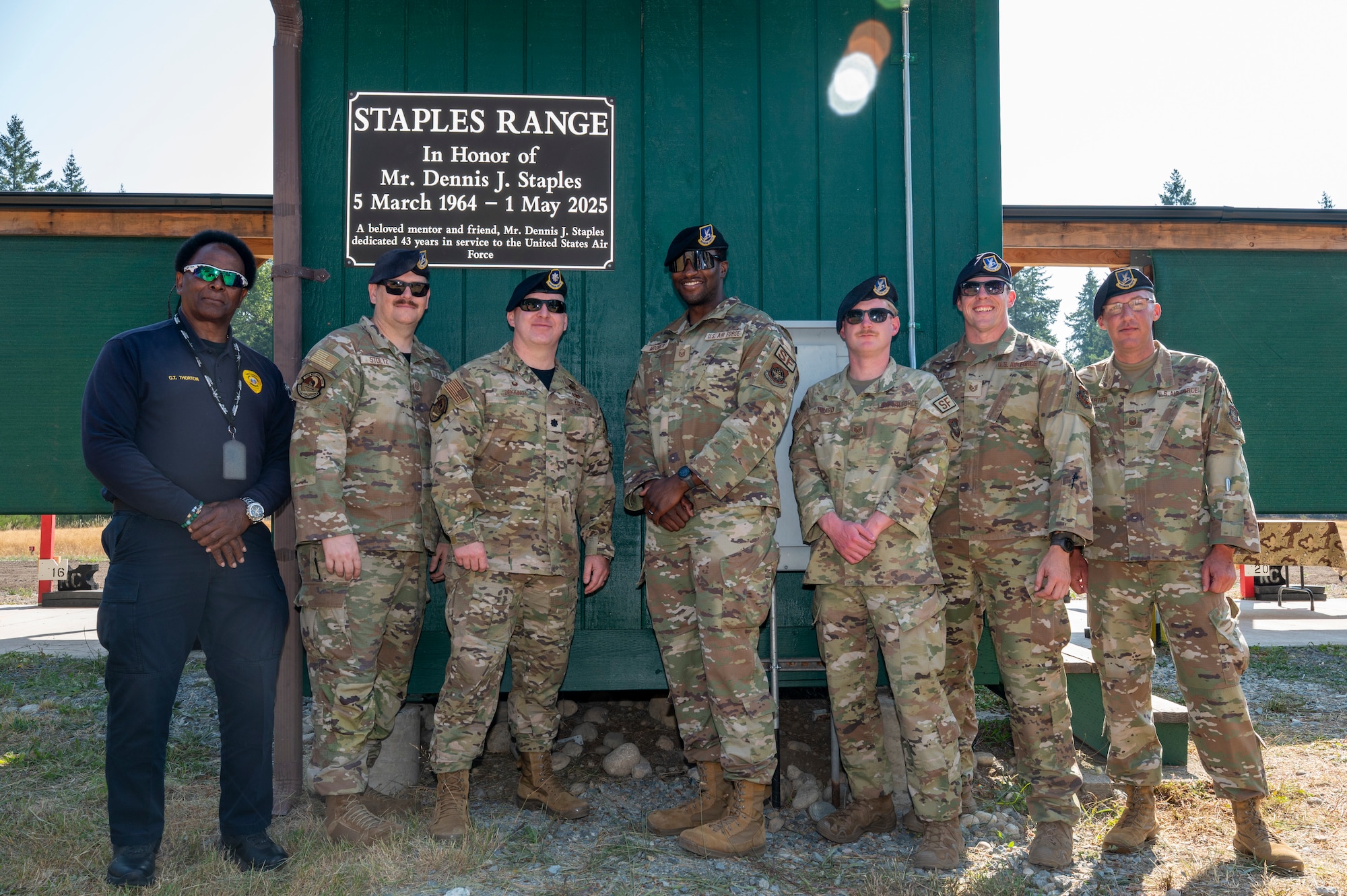 A group of people pose for a photo in front of a plaque.