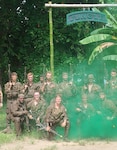 Soldiers pose for a group photo under the Jungle Operations Training sign in Panama June 17. The Jungle Operations Training Course-Panama uses the country’s demanding jungle environment to train U.S., Panamanian and partner-nation forces in jungle warfare, survival skills and interoperability. The course promotes shared tactics, mutual understanding and security cooperation throughout the Western Hemisphere. Photo by Maj. Amanda Russell.