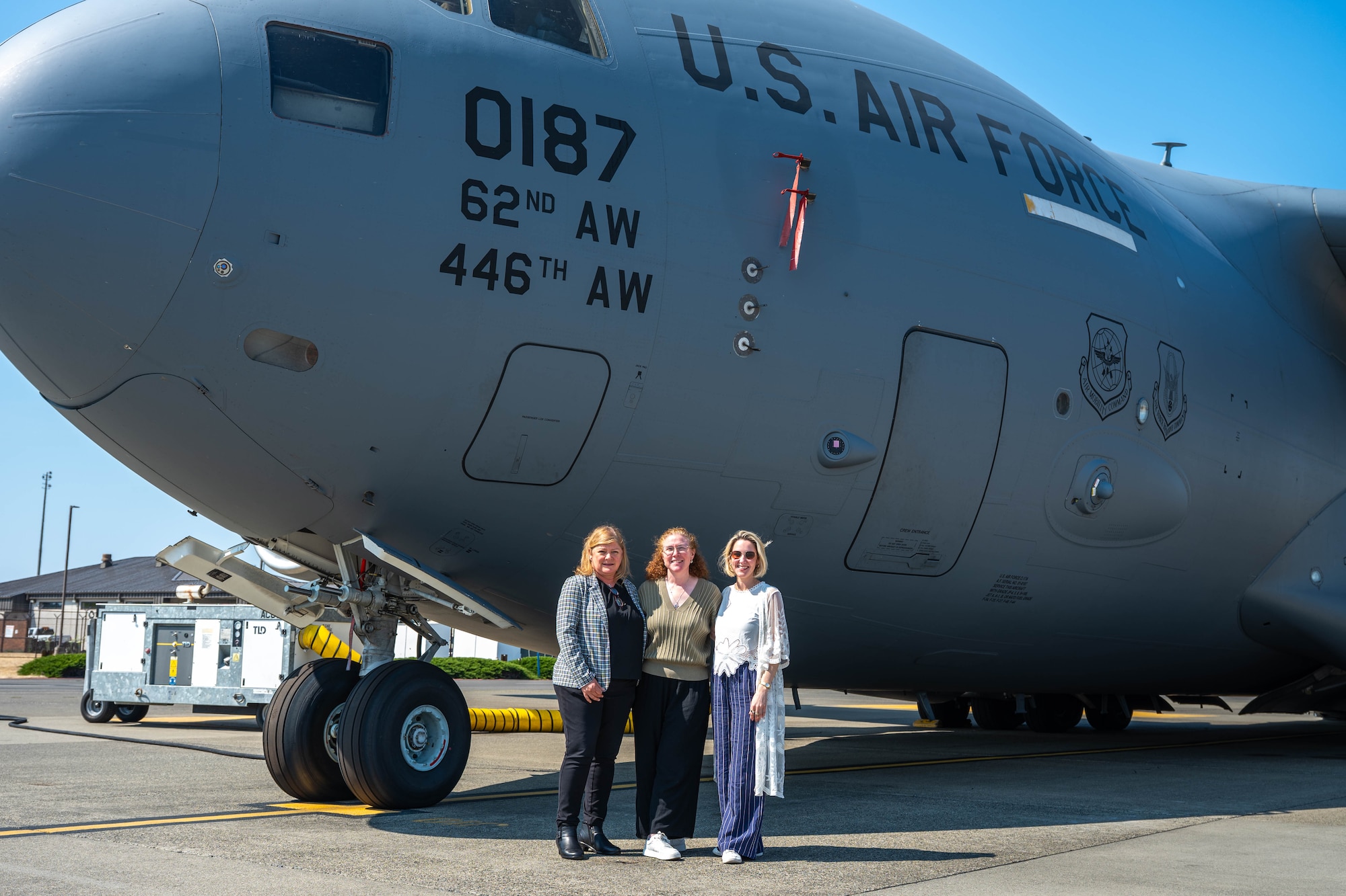 Three people stand under a large aircraft.