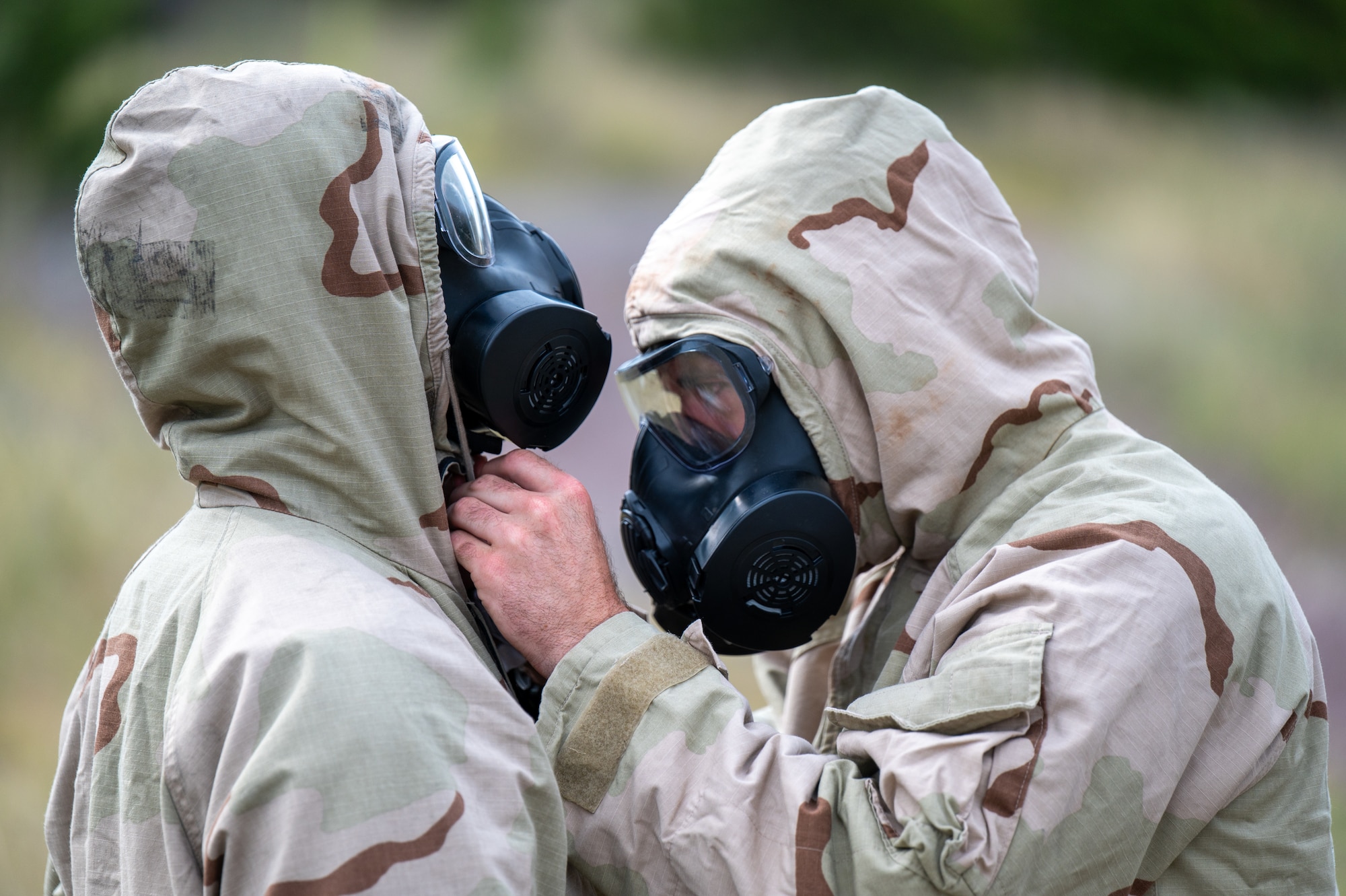 U.S. Air Force Airman 1st Class Levi Womack, 341st Civil Engineer Squadron (CES) explosive ordnance disposal (EOD) technician, right, inspects the gas mask fit on Senior Airman Mitchell Massa, 366th CES EOD technician, during an exercise at Limestone Hills Training Area, Montana, Aug. 18, 2026. Confirming a proper mask seal is critical before entering a contaminated environment, where a compromised fit could expose a technician to chemical hazards. (U.S. Air Force photo by Tech. Sgt. Aaron Thomasson)