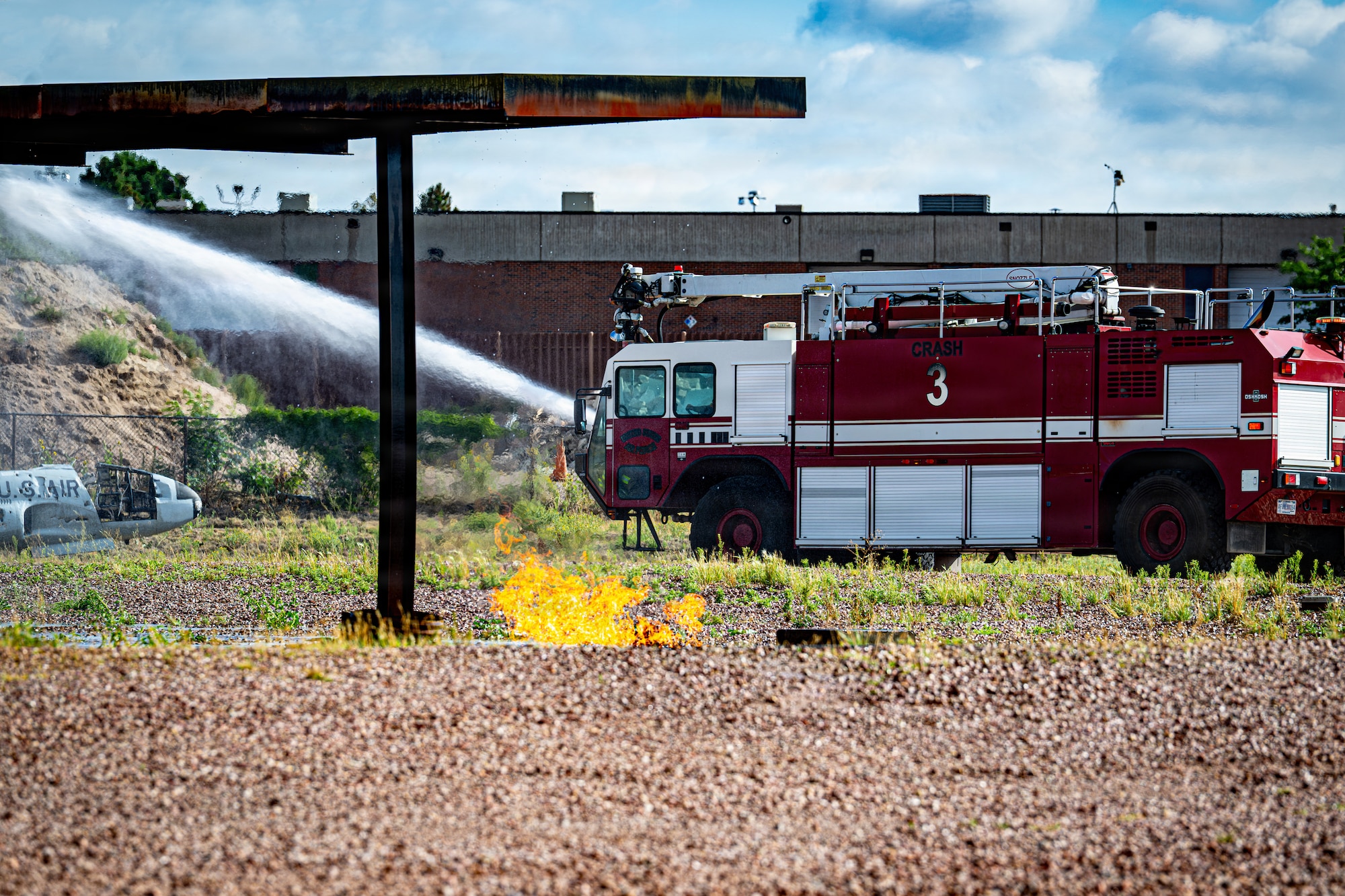 A Peterson Space Force Base Fire Department firefighting vehicle conducts fire suppression operations during a full-scale emergency response exercise