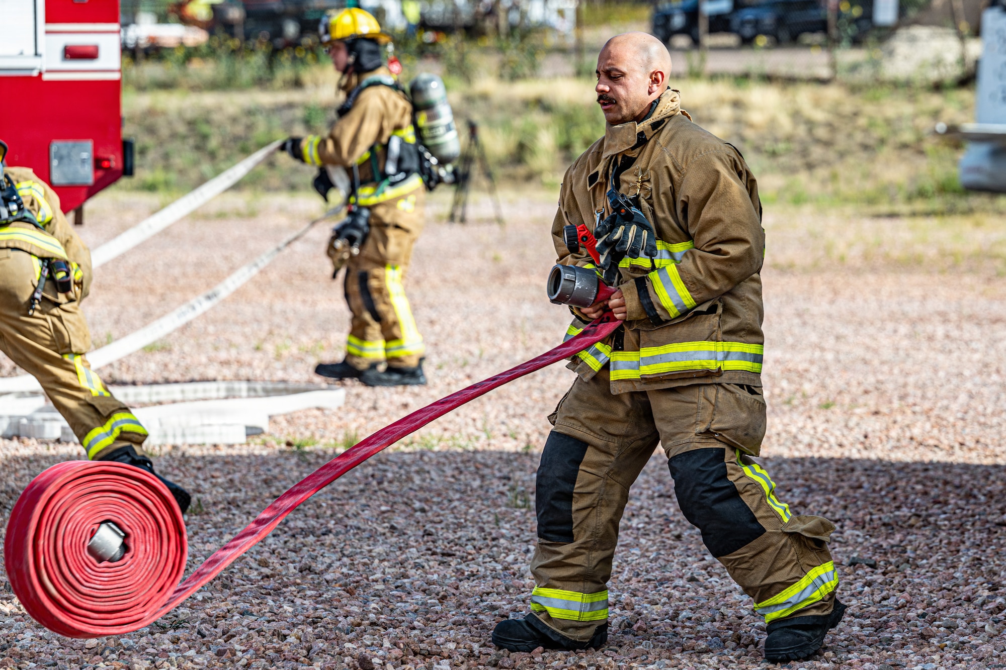A firefighter assigned to the 21st Civil Engineer Squadron deploys a hose line during a full-scale emergency response exercise