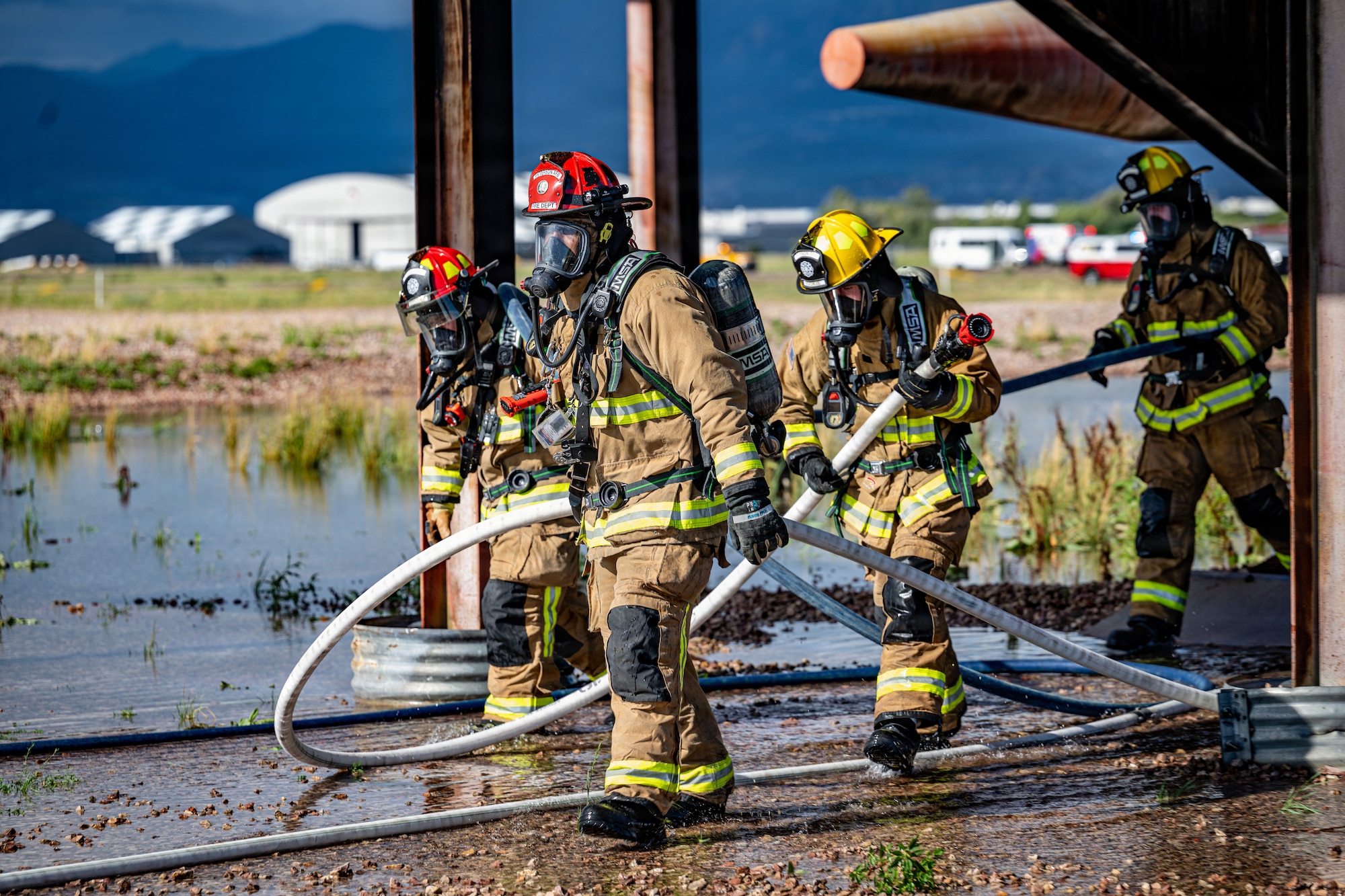 Firefighters assigned to the 21st Civil Engineer Squadron advance hose lines during a full-scale emergency response exercise