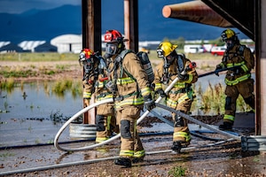 Firefighters assigned to the 21st Civil Engineer Squadron advance hose lines during a full-scale emergency response exercise
