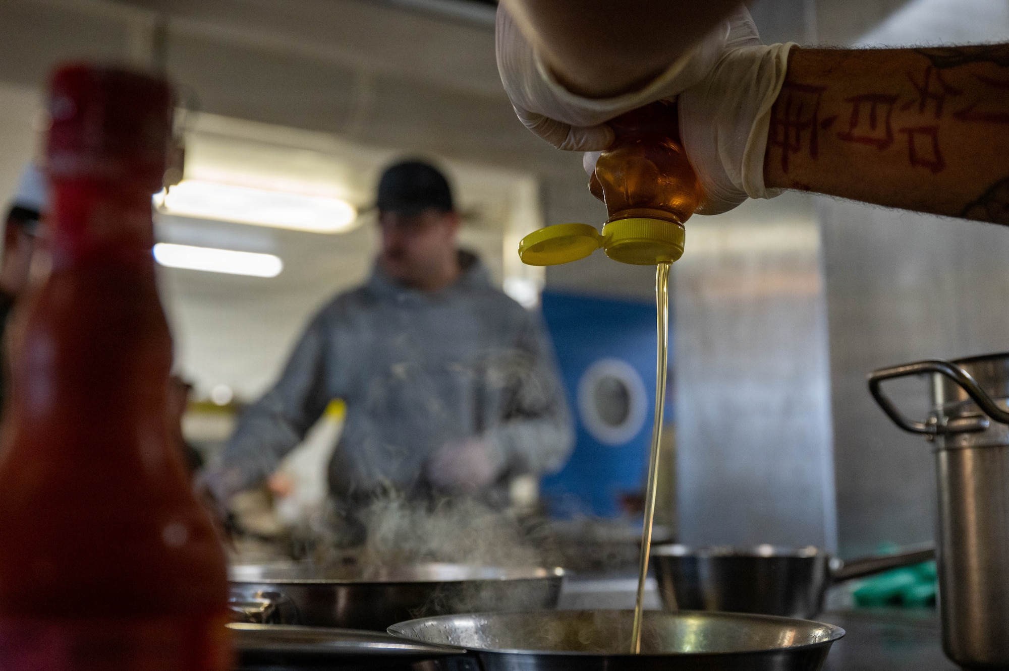 A competitor adds hot honey sauce into their dish during the 786th Force Support Squadron Wing Wars competition at Kapaun Air Station, Germany, Aug. 19, 2026.