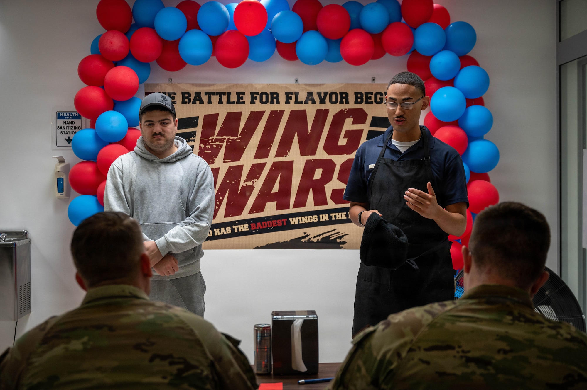 U.S. Air Force Airman 1st Class Cody Danz, 786th Force Support Squadron food service specialist, and U.S. Air Force Senior Airman Javion Haddock, 786th FSS fitness specialist, explain their cooking practices during the 786th Force Support Squadron Wing Wars competition at Kapaun Air Station, Germany, Aug. 19, 2026.