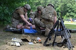 Weapons rest in a stack as explosive ordnance disposal Airmen provide Tactical Combat Casualty Care to a simulated patient at Barnes Air National Guard Base, Westfield, Mass., Aug. 20. EOD Airmen are required to complete Tier 2 TCCC training as part of their job and deployment requirements. Photo by Airman 1st Class Ellen Ozkaptan.