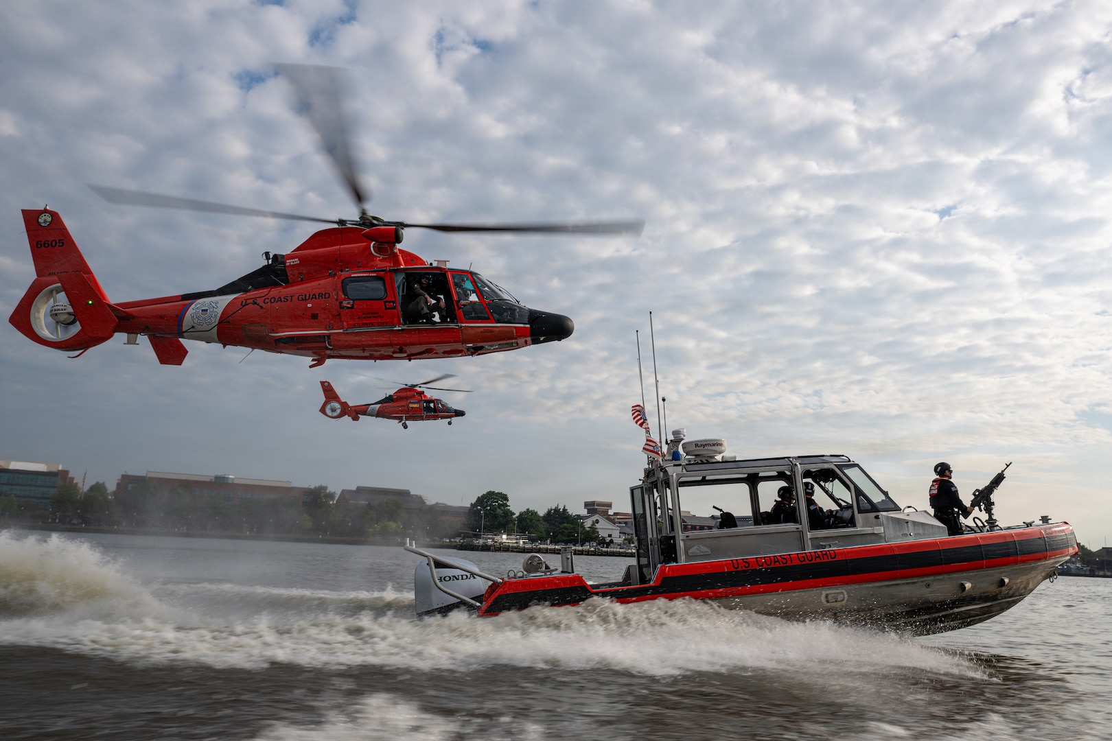 Two Coast Guard MH-65 Dolphin helicopters from Air Station Washington and a Coast Guard 29-foot Response Boat-Small (RB-S) from Station Washington conduct operational maneuvers during a capabilities demonstration on the Potomac River, Aug. 20, 2026. The evolution showcased the crews’ ability to integrate aviation and maritime assets in support of missions across the National Capital Region. (U.S. Coast Guard photo by PA3 Austin Canos)