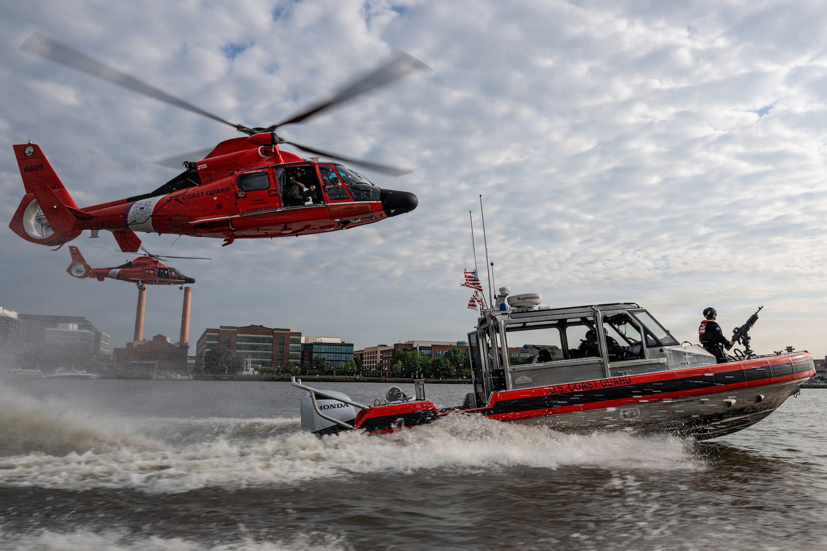 Two Coast Guard MH-65 Dolphin helicopters from Air Station Washington and a Coast Guard 29-foot Response Boat-Small (RB-S) from Station Washington conduct operational maneuvers during a capabilities demonstration on the Potomac River, Aug. 20, 2026. The evolution showcased the crews’ ability to integrate aviation and maritime assets in support of missions across the National Capital Region. (U.S. Coast Guard photo by PA3 Austin Canos)