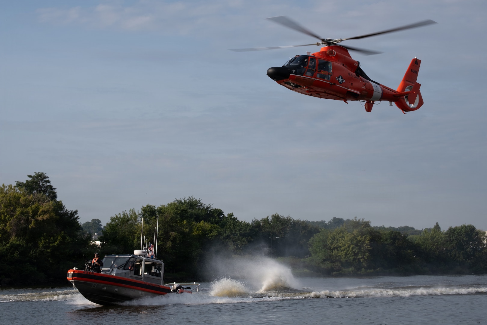 A Coast Guard MH-65 Dolphin helicopter from Air Station Washington and two Coast Guard 29-foot Response Boat-Small (RB-S) boats from Station Washington conduct operational maneuvers during a capabilities demonstration on the Potomac River, Aug. 20, 2026. The evolution showcased the crews’ ability to integrate aviation and maritime assets in support of missions across the National Capital Region. (U.S. Coast Guard photo by PA3 Austin Canos)
