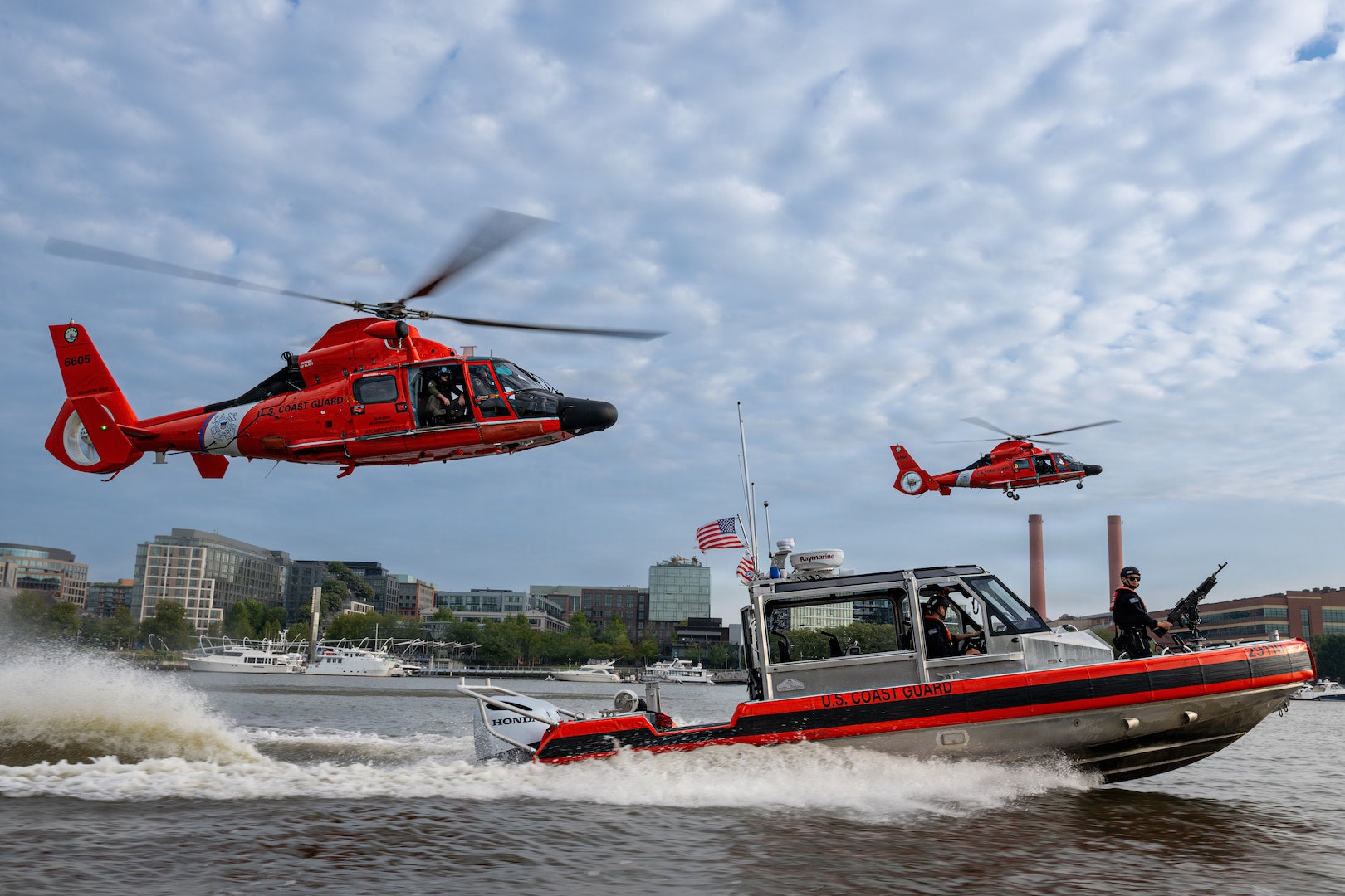 Two Coast Guard MH-65 Dolphin helicopters from Air Station Washington and a Coast Guard 29-foot Response Boat-Small (RB-S) from Station Washington conduct operational maneuvers during a capabilities demonstration on the Potomac River, Aug. 20, 2026. The evolution showcased the crews’ ability to integrate aviation and maritime assets in support of missions across the National Capital Region. (U.S. Coast Guard photo by PA3 Austin Canos)
