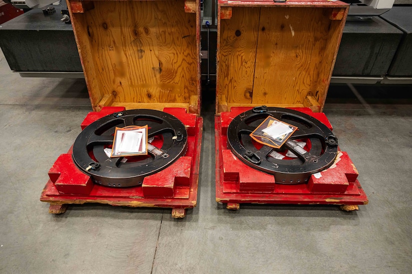 Two missile parts sit inside red pallets on the concrete floor of a warehouse