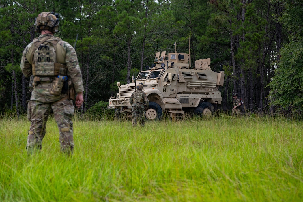 Airman standing watching a military vehicle.
