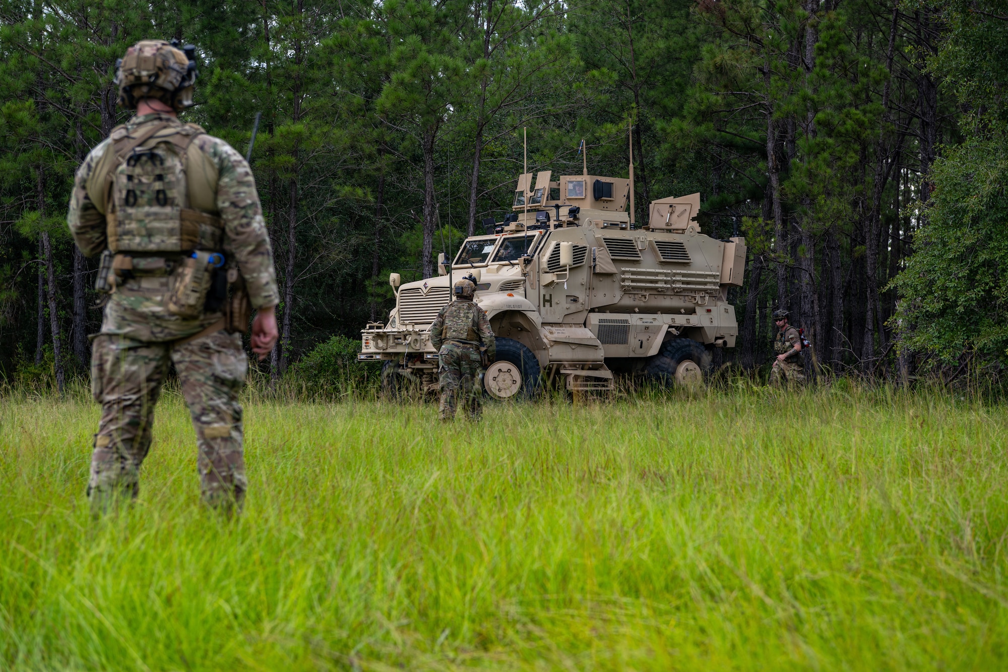 Airman standing watching a military vehicle.