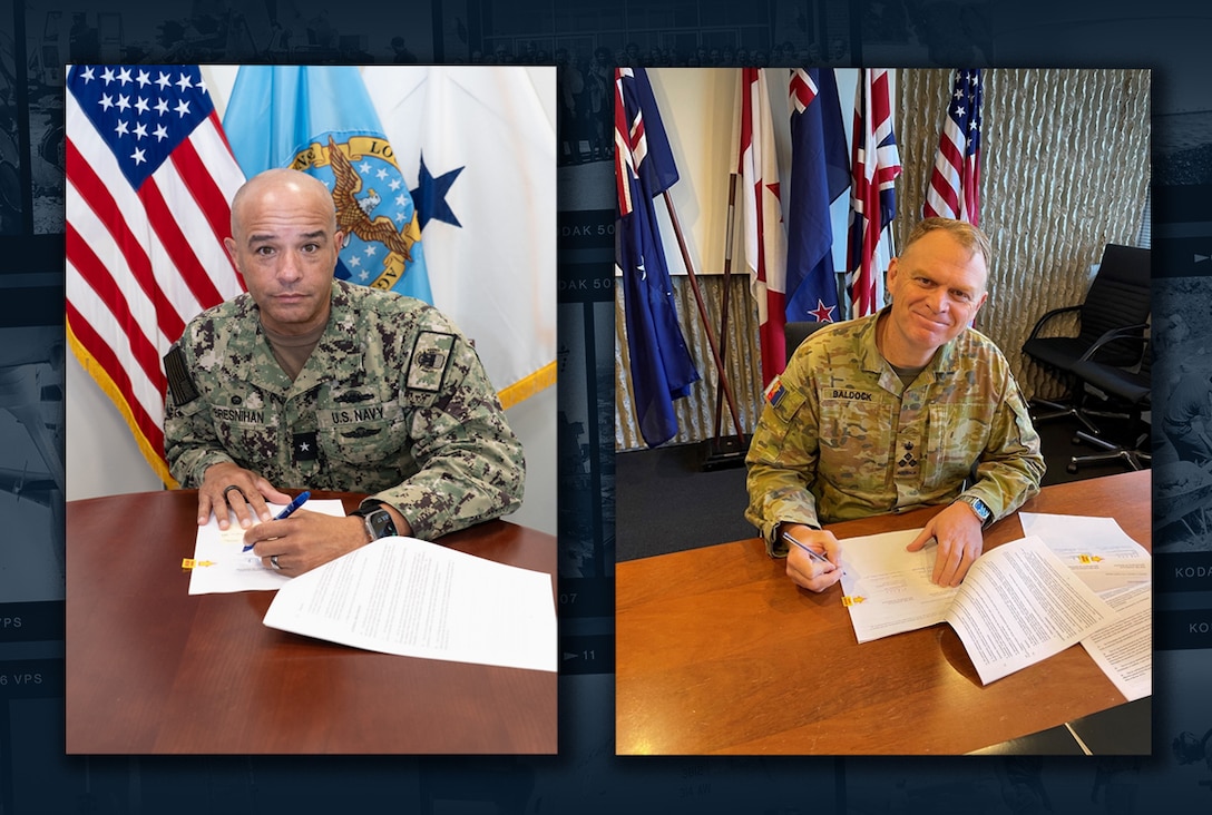 Two men signing papers.
