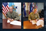 Two men signing papers.