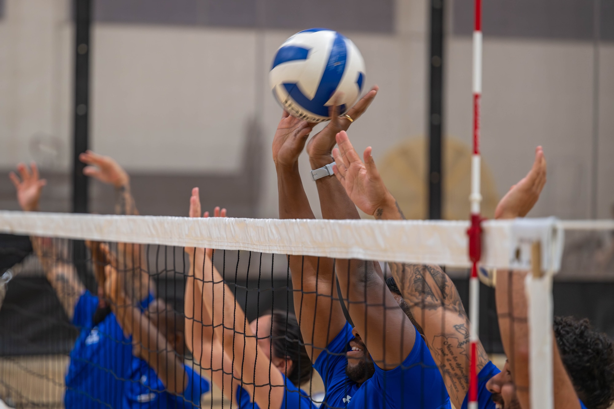 People's hands block a volleyball above a net