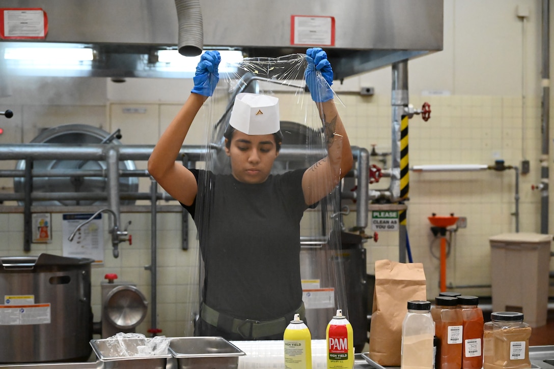 Lance Corporal Jessica Martinez-Flores grabs cling wrap for her team, Marine Corps Base Hawaii, at the fourth quarter fiscal year Marine Corps Installations Pacific Food Services Specialist of the Quarter competition at Combined Arms Training Center, Camp Fuji, August 19, 2026. (U.S. Marine Corps photo by Song Jordan)