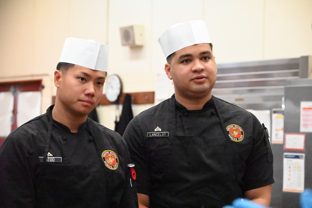 (Right to Left) LCpl. Kaw Htoo and Cpl. Eli Lancelot, chefs assigned to Marine Corps Air Station Iwakuni, listen to pit masters teaching a class about barbecue during the first day of the Marine Corps Installations Pacific Food Services Specialist of the Quarter competition at Combined Arms Training Center, Camp Fuji, August 18, 2026. (U.S. Marine Corps photo by Song Jordan)