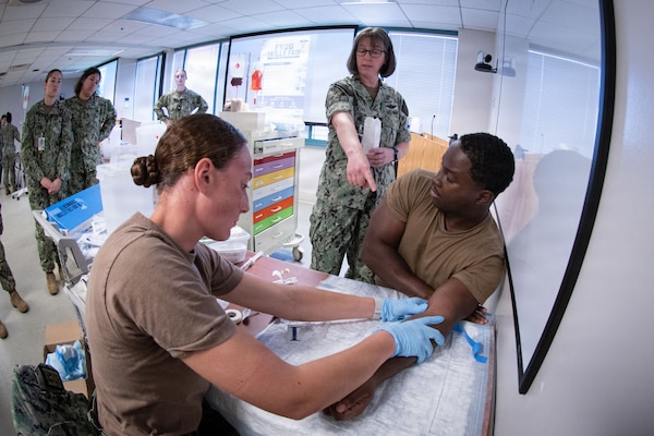 *Training* Navy Capt. Heather Kirk, NMRTC Cherry Point’s Director of Medical Services, center, instructs corpsmen on the proper procedure to insert an IV needle during a skills fair conducted Thursday, August 20, 2026, at Navy Medicine Readiness and Training Command Cherry Point.  The Skills Fair evaluated the knowledge of corpsmen assigned to the facility and trained them on competencies and tasks expected of them in an operational environment.