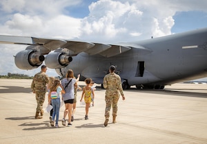 A family walks toward a C-17 Globemaster III aircraft.