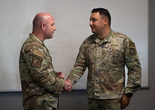 Two men shake hands.