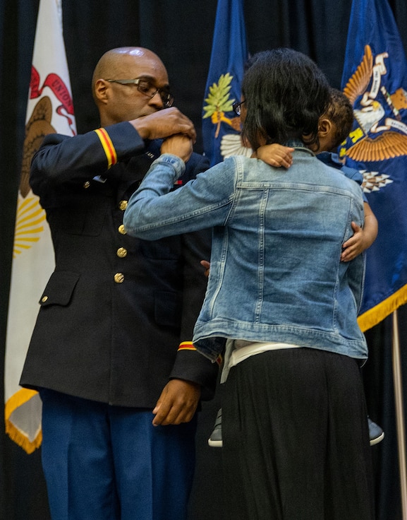 Mariah and Cameron Woods pin second lieutenant rank bars on newly commissioned Illinois Army National Guard (ILARNG) 2nd Lt. Lawrence Woods.