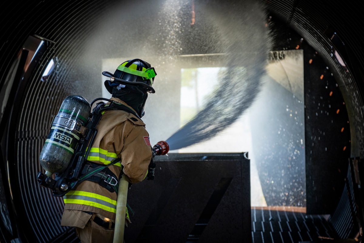 firefighter operates a fire hose during a routine training