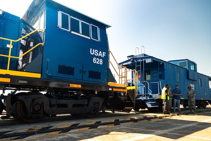 A photo of four people conversing in front of a locomotive.