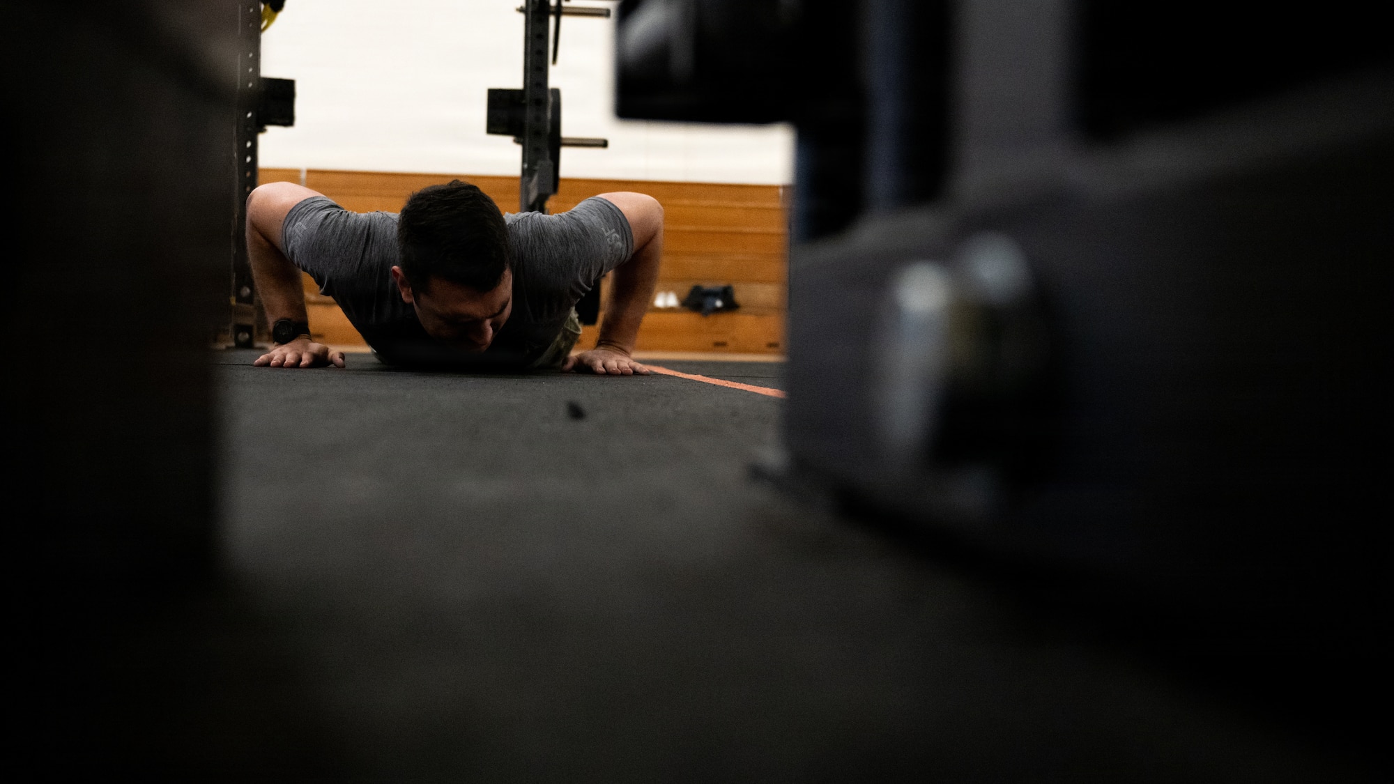 A servicemember does a pushup in a gym.