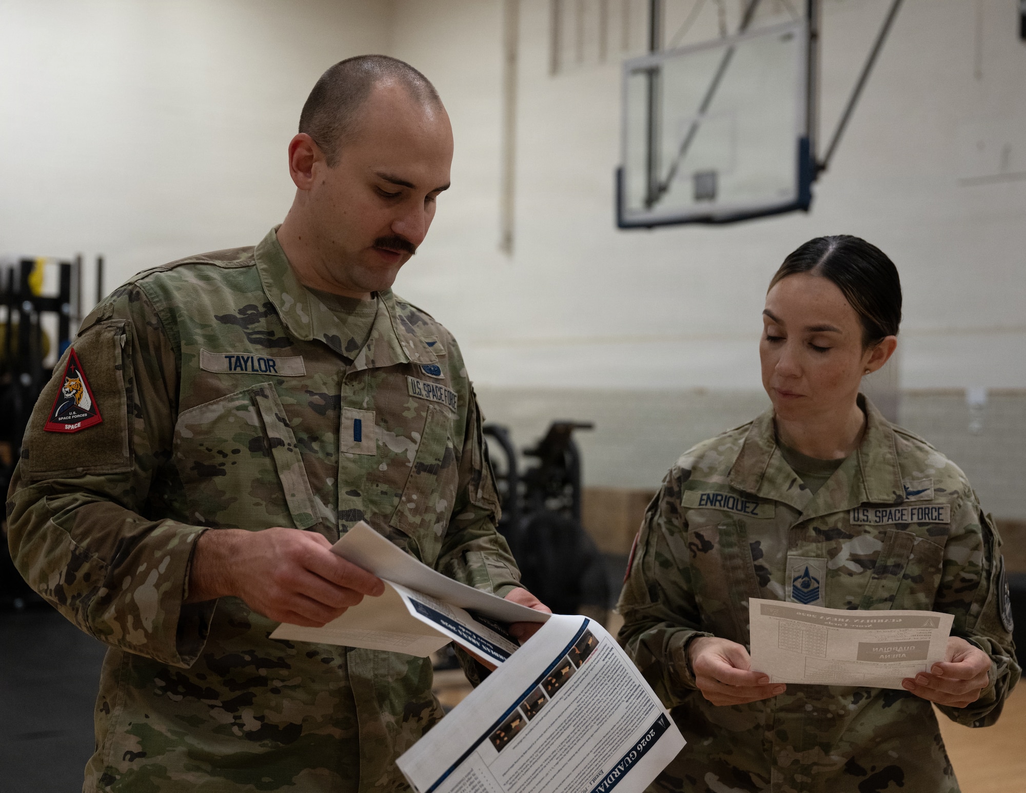 Servicemembers review papers in a gym.